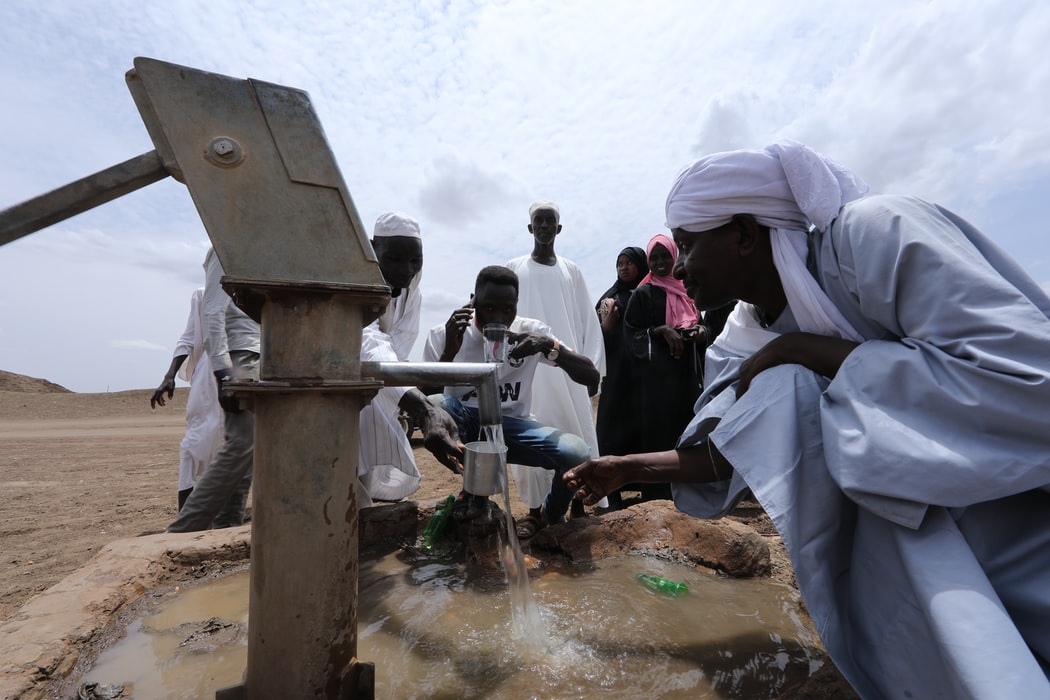 People drinking water on a hand water pump