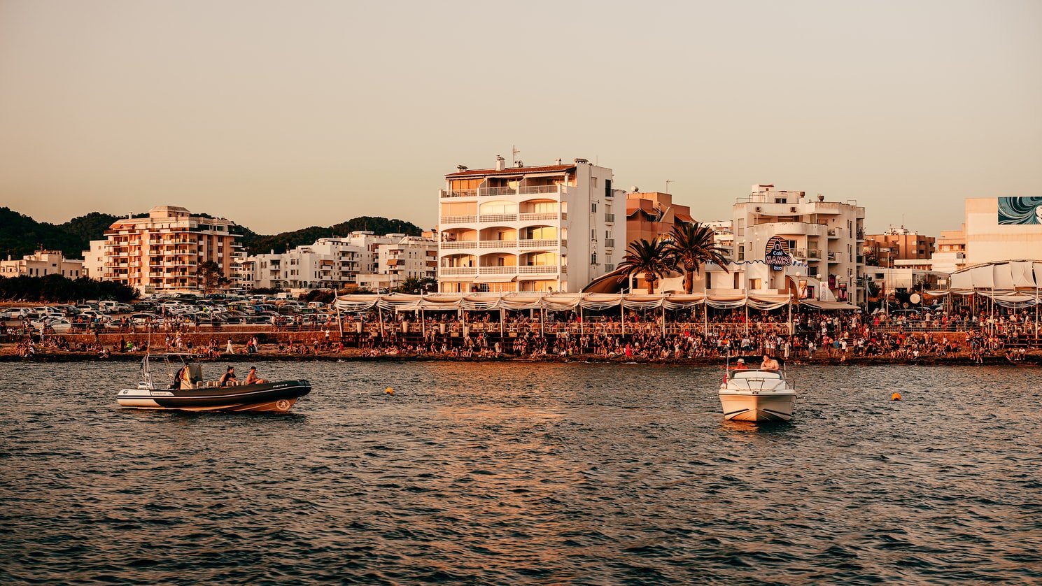 Boats sailing in the sea. Buildings and people ahead.